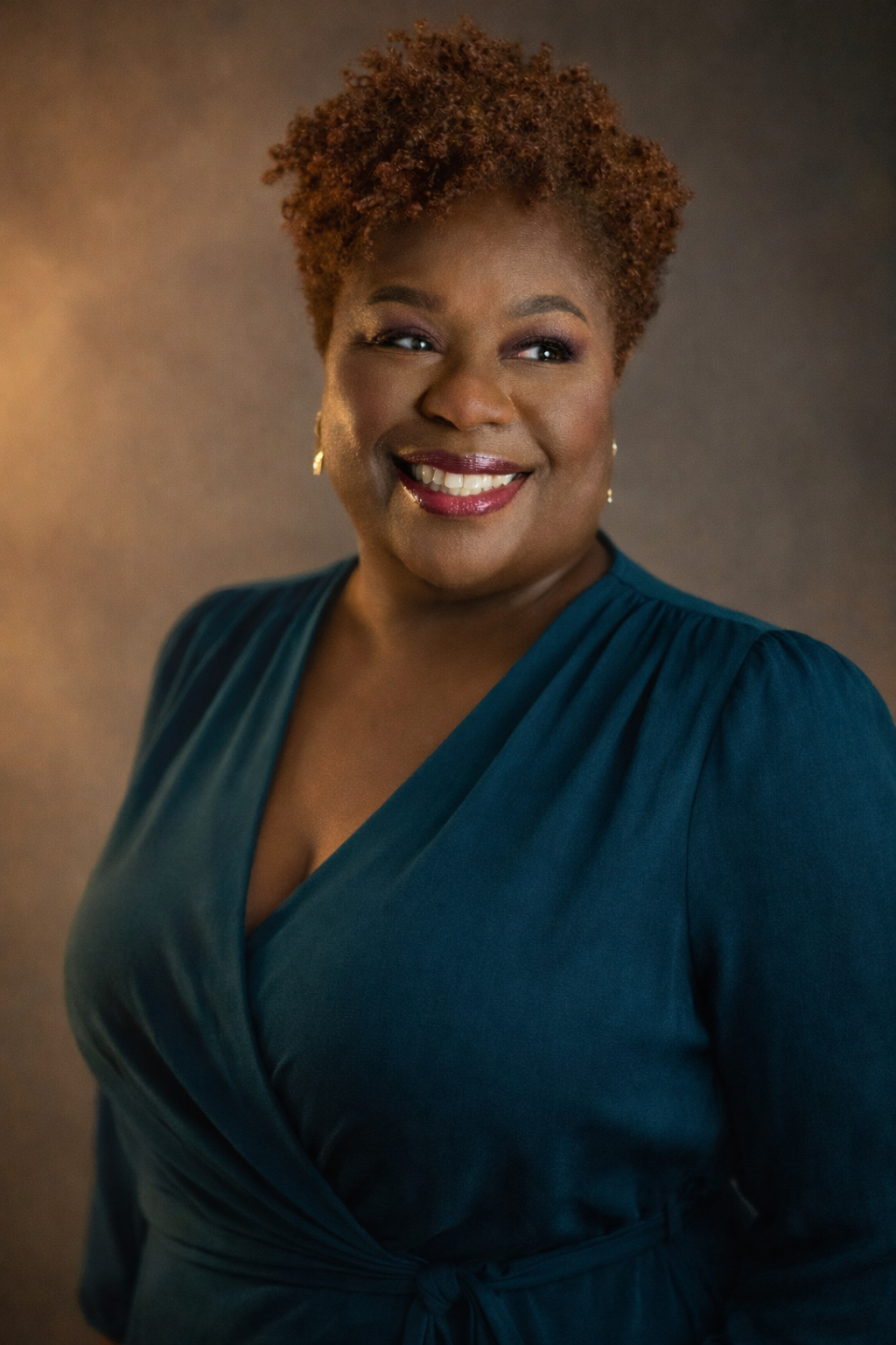 Woman in a teal dress smiling against a brown background